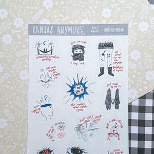 May include: A sheet of stickers with hand-drawn illustrations and text. The stickers feature various designs, including eyes, figures, and phrases like "Kansas Anymore" and "Just Don't Sleep Alone." The background is a floral pattern.