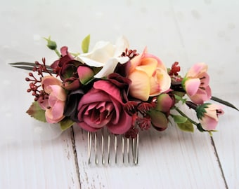 May include: A burgundy, pink, and white floral hair comb with a silver comb. The comb is decorated with a variety of flowers, including roses, carnations, and berries.