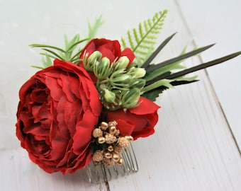 May include: Red silk flower hair comb with gold accents and green leaves. The comb is attached to the back of the flower arrangement.