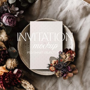 May include: A mockup invitation card with a dotted pattern, placed on a speckled plate. The card is surrounded by dried flowers in shades of burgundy, beige, and purple. The text "INVITATION mockup" is displayed on the card.