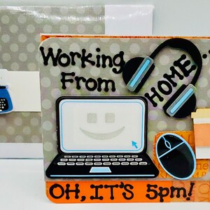 Könnte beinhalten: Eine Karte mit einem Laptop, Kopfhörern, einer Kaffeetasse und einer Maus. Der Text auf der Karte lautet "Von zu Hause arbeiten... Zoom-Meetings, E-Mails checken, Telefonkonferenzen OH, ES IST 17 Uhr!"