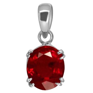 Könnte beinhalten: Ein silberner Anhänger mit einem großen, oval geschliffenen, tiefroten Edelstein. Der Edelstein wird von vier Krappen gehalten. Der Anhänger hat ein schlichtes, elegantes Design, das für den Alltag oder besondere Anlässe geeignet ist.