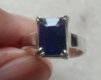 May include: A silver ring with a dark blue rectangular gemstone set in a prong setting.