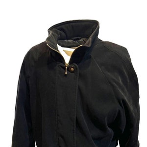 May include: A black suede jacket with a zipper closure, a drawstring waist, and gold-toned hardware.