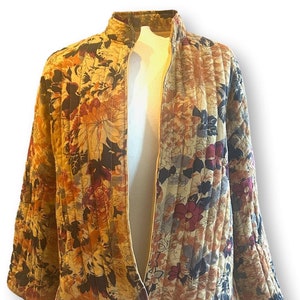 May include: A quilted jacket with a floral print in shades of brown, yellow, and pink. The jacket has a stand-up collar and a zipper closure.