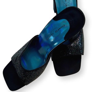 May include: Pair of black sparkly heeled sandals with a blue insole. The insole has the text "Chinese Laundry" printed on it.