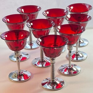 May include: Set of ten red glass cocktail glasses with silver metal stems. The glasses have a fluted design and are perfect for serving cocktails or other beverages.