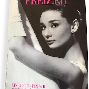 May include: A black and white magazine cover featuring Audrey Hepburn with the title "FREIZEIT KURIER" and the text "EINE FRAU - EIN STIL. Aparte Schönbeit: Audrey Hepburn verzaubert die Modewelt bis heute."