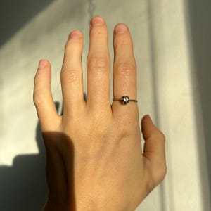 K&ouml;nnte beinhalten: Ein silberner Ring mit einem kleinen, runden, klaren Stein in der Mitte.