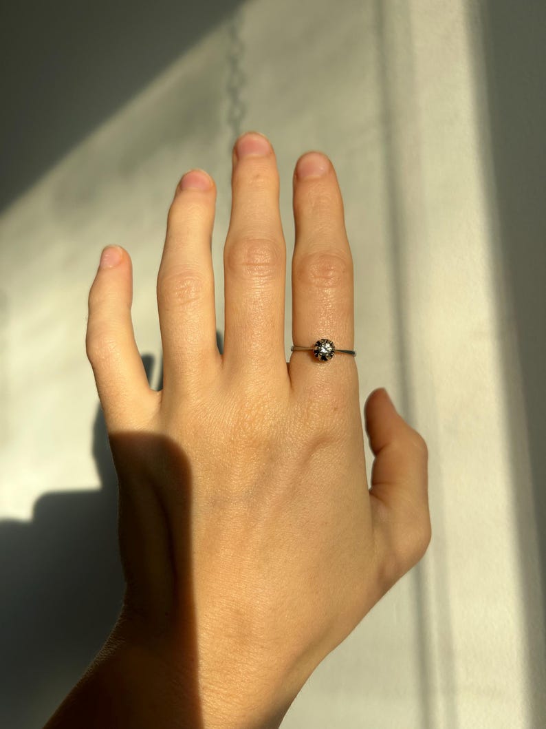 K&ouml;nnte beinhalten: Ein silberner Ring mit einem kleinen, runden, klaren Stein in der Mitte.