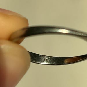 K&ouml;nnte beinhalten: Nahaufnahme des Innenbereichs eines silbernen Bandrings. Der Ring hat eine kleine Inschrift auf der Innenseite.