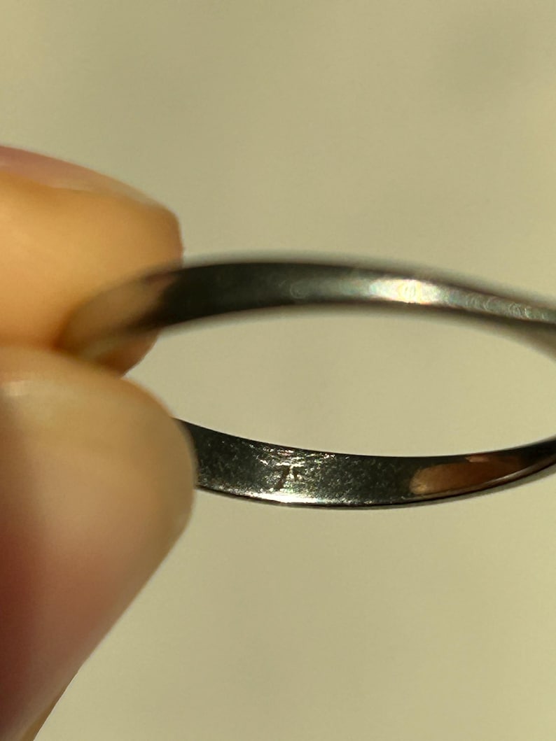 K&ouml;nnte beinhalten: Nahaufnahme des Innenbereichs eines silbernen Bandrings. Der Ring hat eine kleine Inschrift auf der Innenseite.