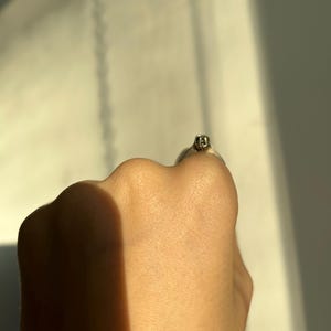 K&ouml;nnte beinhalten: Nahaufnahme eines silbernen Rings mit einem kleinen, klaren Stein in der Mitte.