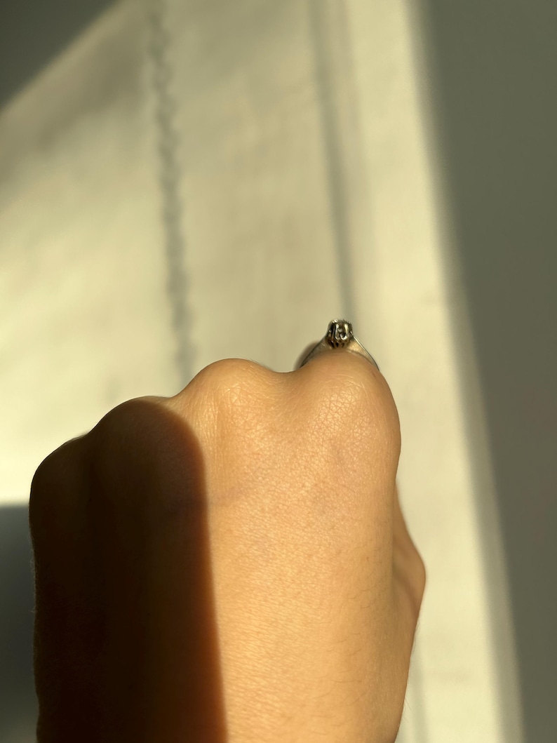 K&ouml;nnte beinhalten: Nahaufnahme eines silbernen Rings mit einem kleinen, klaren Stein in der Mitte.