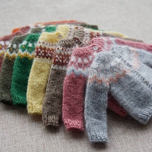 Può includere: Una collezione di cardigan di lana colorati con una varietà di motivi, tra cui strisce e disegni geometrici.