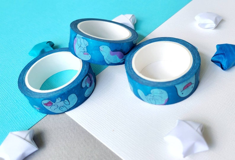 May include: Three rolls of blue washi tape with a white background. The tape has a pattern of cartoon sea creatures in shades of blue and purple.