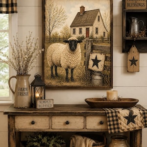May include: A rectangular wall art print featuring a sheep standing in front of a house, a wooden fence, and a black star sign. The artwork is displayed in a dark wooden frame and depicts a rural scene with a cream-coloured house and a black-faced sheep.
