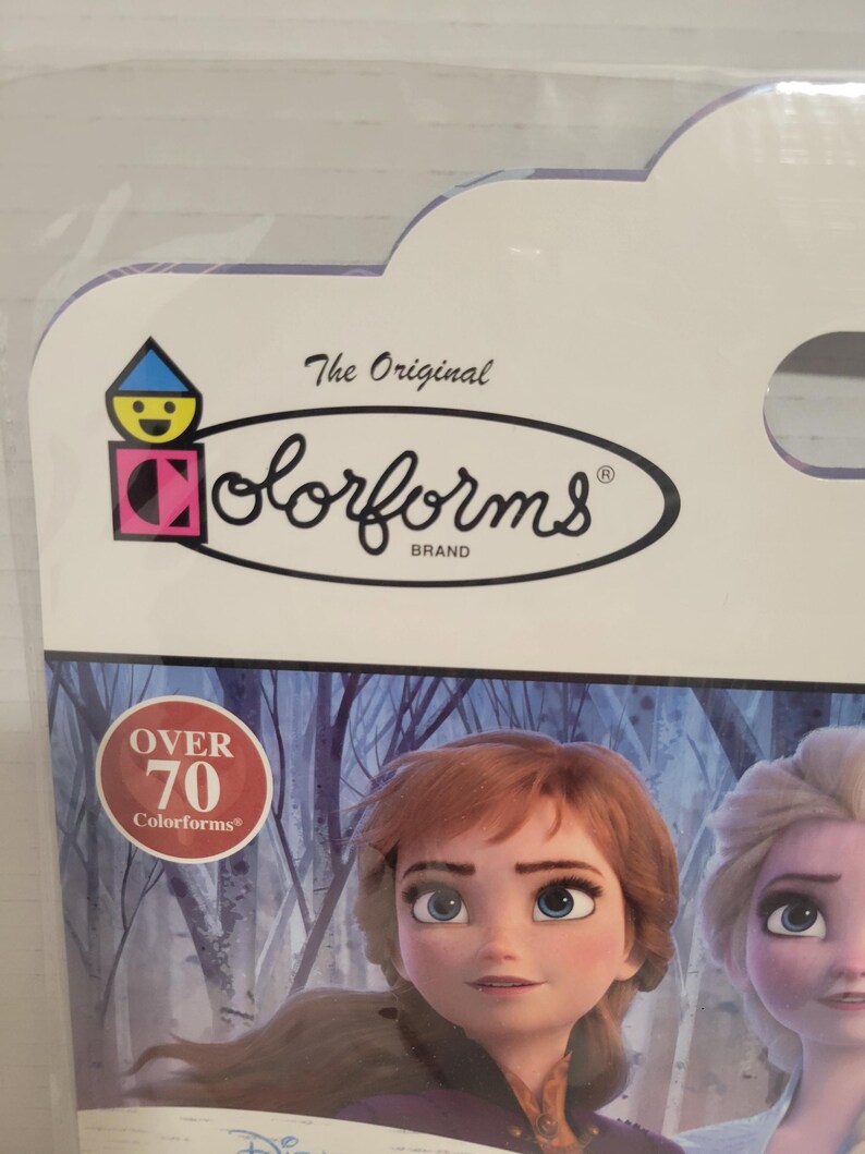 May include: A package of Colorforms featuring the characters Anna and Elsa from the Disney movie Frozen. The package has a blue and white background with a red circle that says "Over 70 Colorforms".