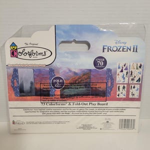 May include: A box of Colorforms featuring characters from Disney's Frozen II. The box is blue and purple with a picture of Elsa and Anna on the front. The back of the box has a warning about plastic bags and information about the product. The box includes 73 Colorforms and a fold-out play board.