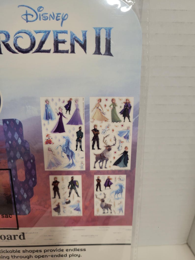 May include: A set of Frozen II stickers featuring characters from the movie, including Elsa, Anna, Kristoff, Olaf, and Sven. The stickers are on a white background with a blue and purple border.