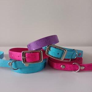 Puede incluir: Una colección de collares para perros en colores vibrantes: rosa, azul y morado. Cada collar tiene una hebilla plateada y una anilla en D a juego. Los collares están hechos de un material texturizado.
