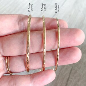 May include: Three gold hammered metal hoops of different sizes. The hoops are 2.9mm, 2.2mm, and 1.8mm in diameter. The hoops are arranged from largest to smallest.