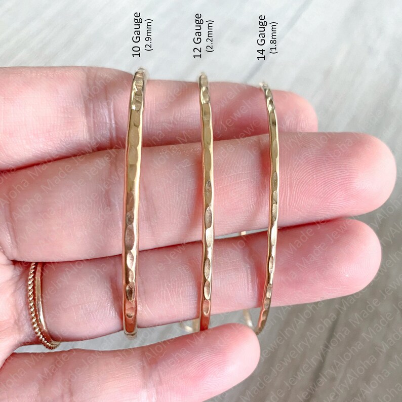 May include: Three gold hammered metal hoops of different sizes. The hoops are 2.9mm, 2.2mm, and 1.8mm in diameter. The hoops are arranged from largest to smallest.