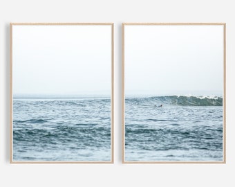 May include: Two framed photographs of a blue ocean with waves crashing. The left photo shows a calm ocean with a horizon in the distance. The right photo shows a surfer riding a wave.