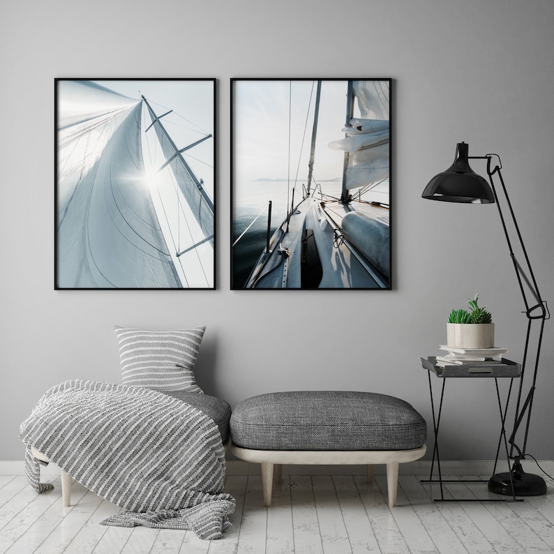 May include: Two framed photographs of a sailboat with white sails against a blue sky and water. The first photo shows the sail from the side, while the second photo shows the deck of the boat.