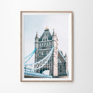 May include: A photograph of Tower Bridge in London, England. The bridge is made of stone and metal, and it has two towers on either side of the road. The towers are topped with spires, and the bridge is painted in a light blue color.