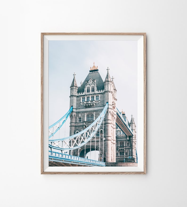 May include: A photograph of Tower Bridge in London, England. The bridge is made of stone and metal, and it has two towers on either side of the road. The towers are topped with spires, and the bridge is painted in a light blue color.