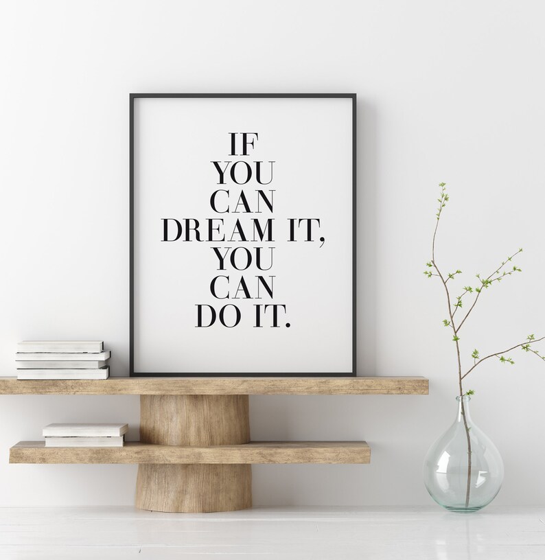 May include: Black and white motivational quote print in a black frame on a wooden shelf with a clear glass vase and a branch with green leaves. The quote reads "If you can dream it, you can do it."
