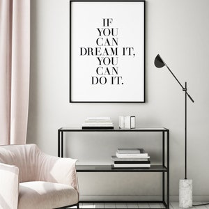 May include: Black and white motivational quote print in a black frame, hanging on a white wall. The quote reads "If you can dream it, you can do it."