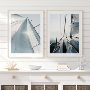 May include: Two framed photographs of a sailboat on the water. The first photo shows the sail billowing in the wind. The second photo shows the deck of the boat.
