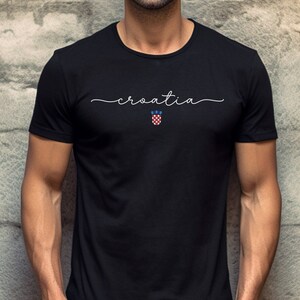 May include: Black t-shirt with white text that says "croatia" and a small Croatian coat of arms.