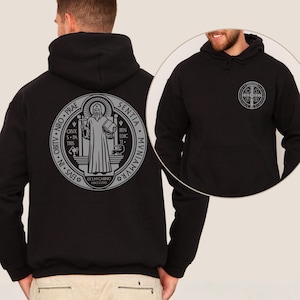 May include: Black hooded sweatshirt with a large gray emblem on the back and a smaller emblem on the front. The emblem features a religious figure holding a book and cross, surrounded by text. The sweatshirt has a front pocket and a hood.