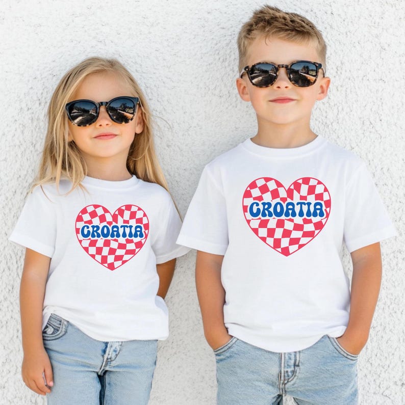 May include: Two children wearing white t-shirts with a red and white checkered heart design that says "CROATIA" in blue letters. The children are wearing blue jeans and sunglasses.