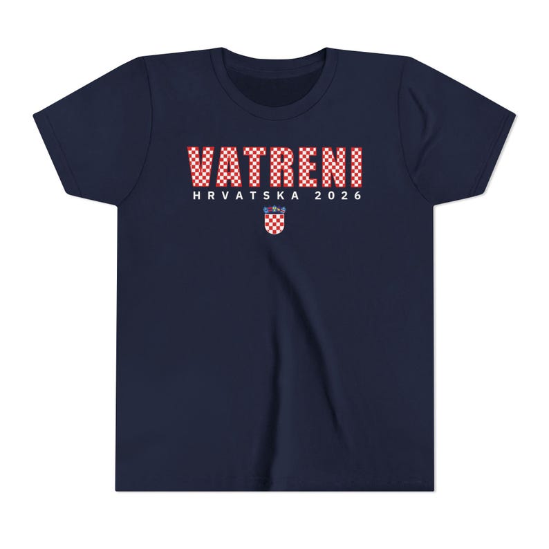May include: Navy blue t-shirt with the text "VATRENI HRVATSKA 2026" in red and white checkered letters. A Croatian coat of arms is below the text. The shirt is a youth size.