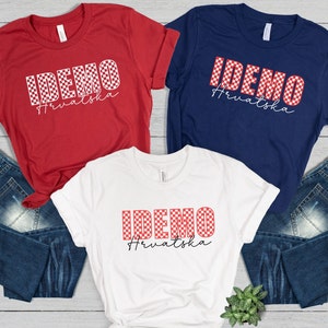 May include: Three t-shirts with the text "IDEMO Hrvatska" in a checkered pattern. The shirts are red, white, and navy blue. The text is in white and the checkered pattern is red and white.