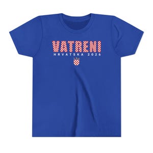May include: Royal blue t-shirt with the word "VATRENI" in a red and white checkered pattern. Below the word is "HRVATSKA 2026" in white text, and a Croatian coat of arms. The shirt is a youth size.