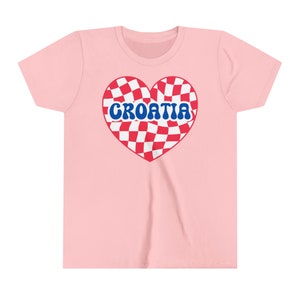 May include: Pink t-shirt with a red and white checkered heart design and the word "CROATIA" in blue letters.