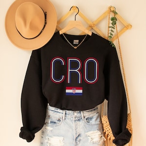 May include: Black sweatshirt with the word "CRO" in red, white and blue outlined letters. The Croatian flag is below the word.