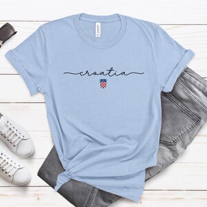 May include: Light blue t-shirt with the word "croatia" written in cursive and a small Croatian coat of arms graphic.