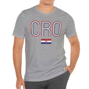 May include: A heather grey t-shirt with the word "CRO" in red, white, and blue outlined letters. The Croatian flag is printed below the word.