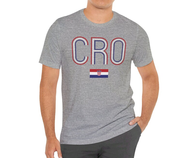 May include: A heather grey t-shirt with the word "CRO" in red, white, and blue outlined letters. The Croatian flag is printed below the word.