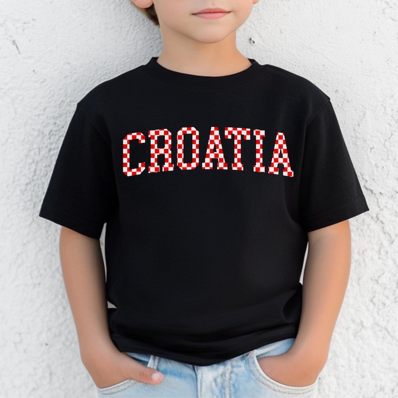 May include: Black t-shirt with the word "CROATIA" in red and white checkered letters. The shirt is short-sleeved and appears to be made of cotton. The design is centered on the chest.