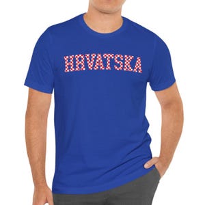 May include: A royal blue t-shirt featuring the word "HRVATSKA" in a red and white chequered design. The short-sleeved shirt is made of a soft fabric.
