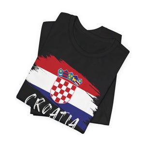 K&ouml;nnte beinhalten: Schwarzes T-Shirt mit einem kroatischen Flaggen-Design in Wei&szlig;, Rot und Blau. Die Flagge enth&auml;lt ein Wappen und das Wort "CROATIA" ist in Wei&szlig; auf dem T-Shirt geschrieben.