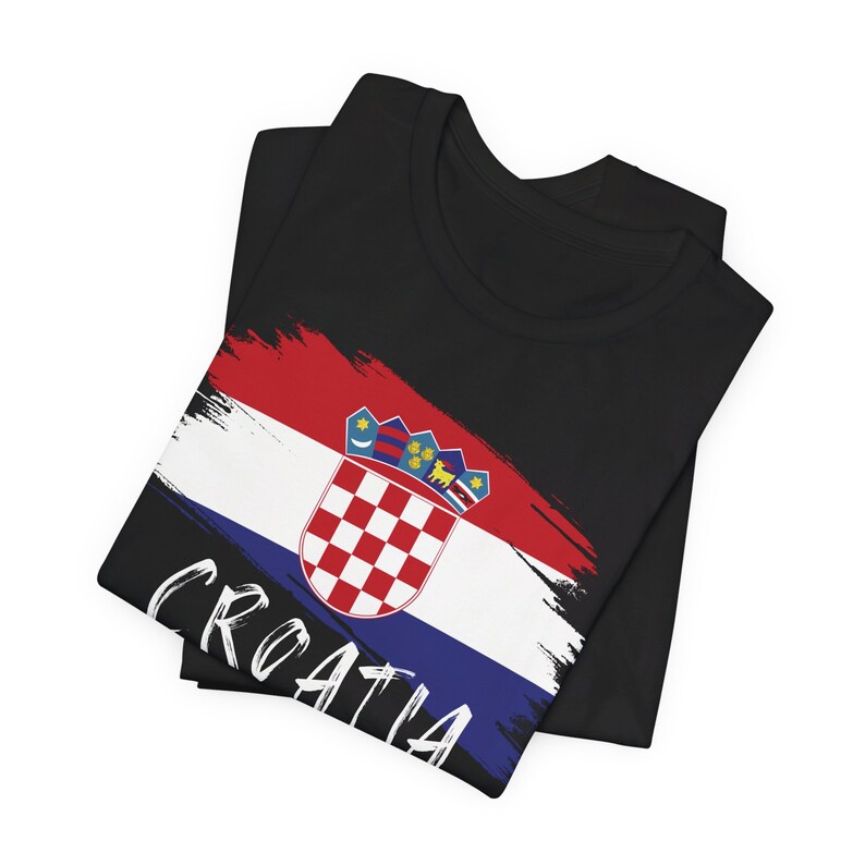 K&ouml;nnte beinhalten: Schwarzes T-Shirt mit einem kroatischen Flaggen-Design in Wei&szlig;, Rot und Blau. Die Flagge enth&auml;lt ein Wappen und das Wort "CROATIA" ist in Wei&szlig; auf dem T-Shirt geschrieben.