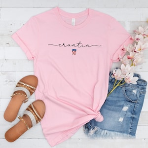 May include: Pink t-shirt with the word "croatia" written in cursive with the Croatian coat of arms underneath.